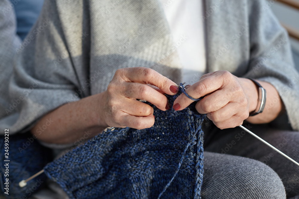 Φωτογραφία Unrecognizable elderly senior woman wearing wide gray scarf and wrist watch, knitting sweater