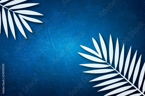 Palm leaves made of paper on blue wall background 