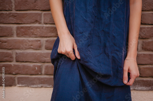 woman wearing long blue dress stands near brick wall © Kristina