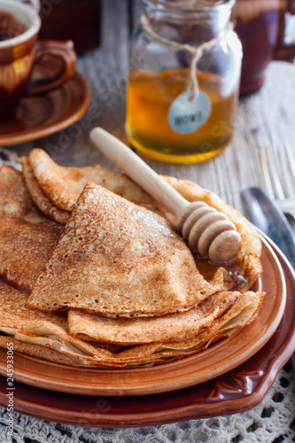 Homemade Russian openwork pancakes for carnival in honey, selective focus