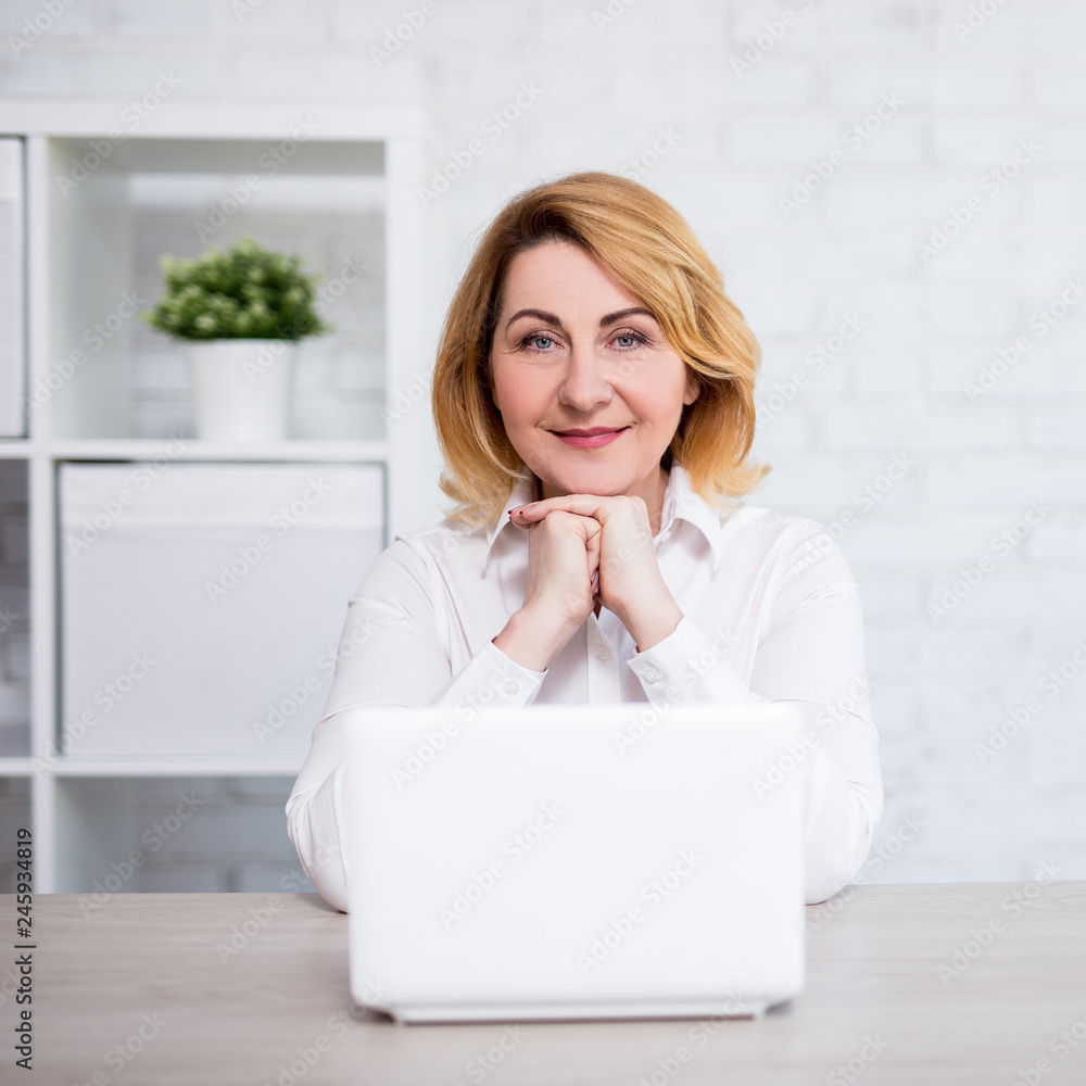 mature woman sitting with laptop in modern office or living room mature woman sitting with laptop in modern office or living room