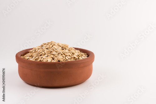 Dry rolled oatmeal in bowl isolated on white background.