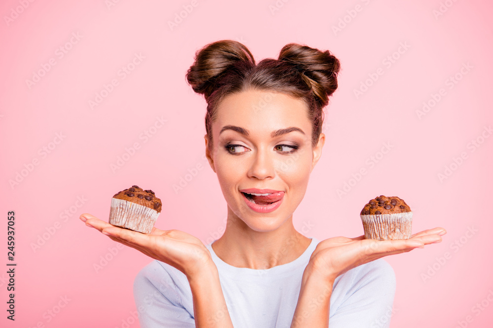 Close-up portrait of nice lovely cute fascinating attractive cheerful hungry foxy girl holding in hands two cakes choosing deciding isolated over pink pastel background Close-up portrait of nice lovely cute fascinating attractive cheerful hungry foxy girl holding in hands two cakes choosing deciding isolated over pink pastel background