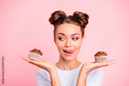Close-up portrait of nice lovely cute fascinating attractive cheerful hungry foxy girl holding in hands two cakes choosing deciding isolated over pink pastel background