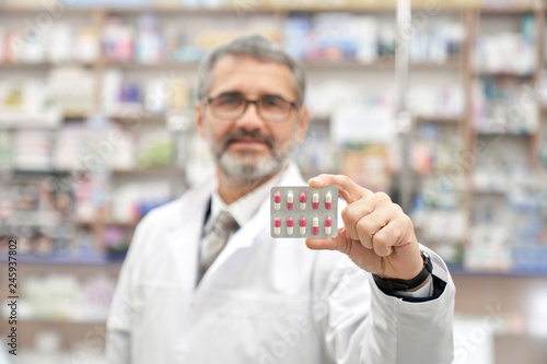 Chemist holding blister pack with pills.
