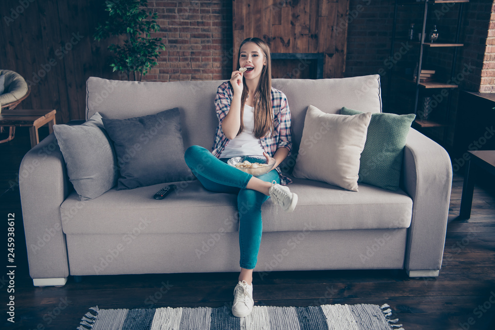 Obraz premium Full body length size photo portrait of cheerful positive interested charming she her teenager teen girl having recreation on divan tasting fast food from plate in hands