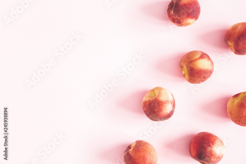 Peaches on pastel pink background. Frame made of fresh peaches. Flat lay, top view, copy space
