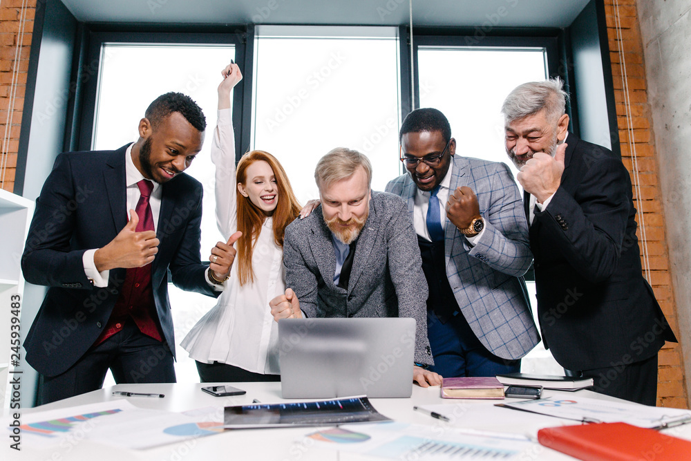 Business ethnic people are happy with the successful signing of the contract standing at the table in front of a laptop in a modern office. Business concept Business ethnic people are happy with the successful signing of the contract standing at the table in front of a laptop in a modern office. Business concept