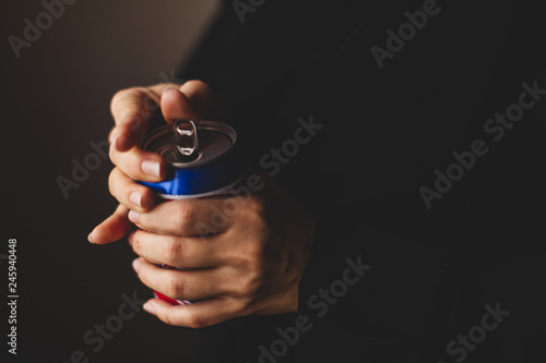 Woman's hand opening red and blue aluminum can. 