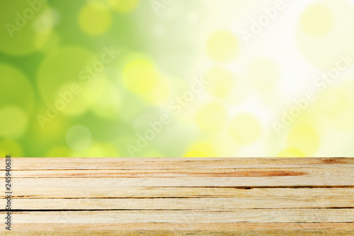 Empty wooden deck table with foliage bokeh.