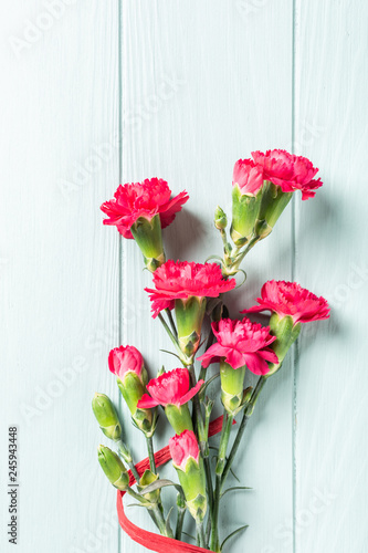 Fototapeta Naklejka Na Ścianę i Meble -  Bouquet of pink carnation on light turquoise wooden background. Top view with copy space.