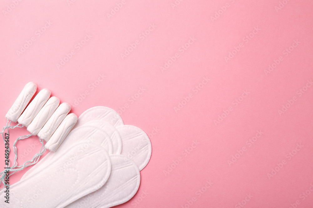women intimate hygiene products - sanitary pads and tampons on pink background, copy space