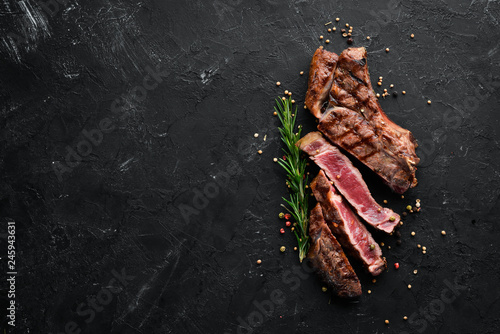Veal steak on a bone on a black background. Free space for your text. Top view.