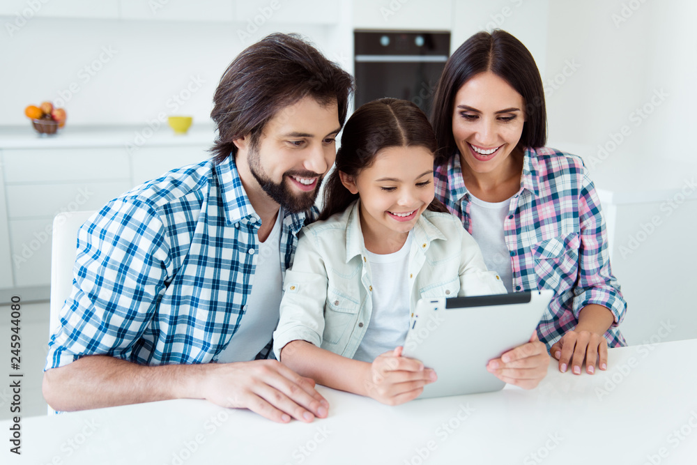 Portrait of nice cute attractive cheerful cheery positive people mom dad spending time using new gadget device reading e-book online in light white modern interior indoors Portrait of nice cute attractive cheerful cheery positive people mom dad spending time using new gadget device reading e-book online in light white modern interior indoors