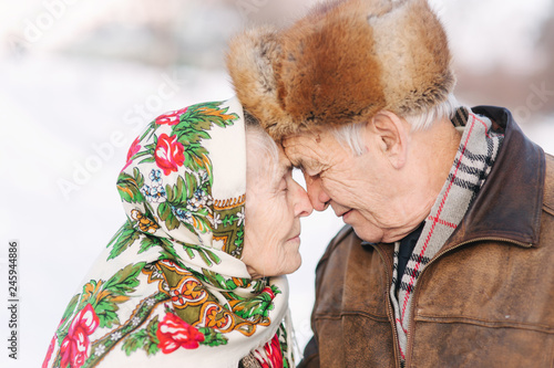 Portrait of happy senior couple. Elderly woman kiss her husband in weighty. old couple walkink in the park in winter time. Happy family. Gold wedding photo