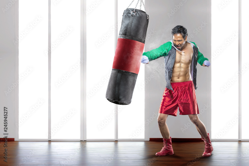Young asian sportsman with boxing gloves punch the boxing bag