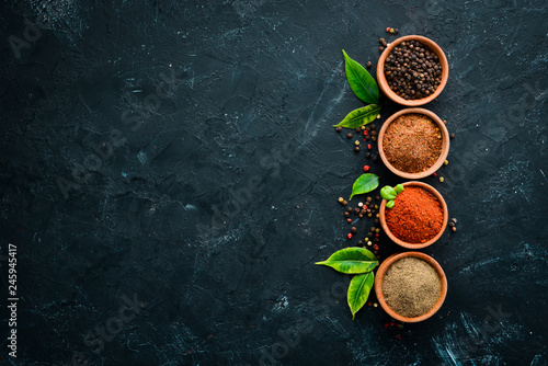 A set of peppers. Black pepper, colored pepper, ground pepper, dried chili pepper. Top view. On a black background. free space for your text.