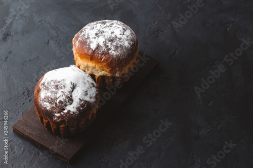 Homemade muffins with sugar powder on the dark, textured background