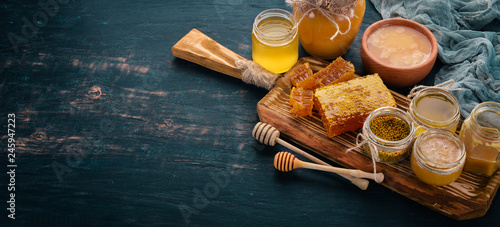 A set of honey and bee products. Honey in honeycomb. On a black wooden background. Free space for text. Top view. photo