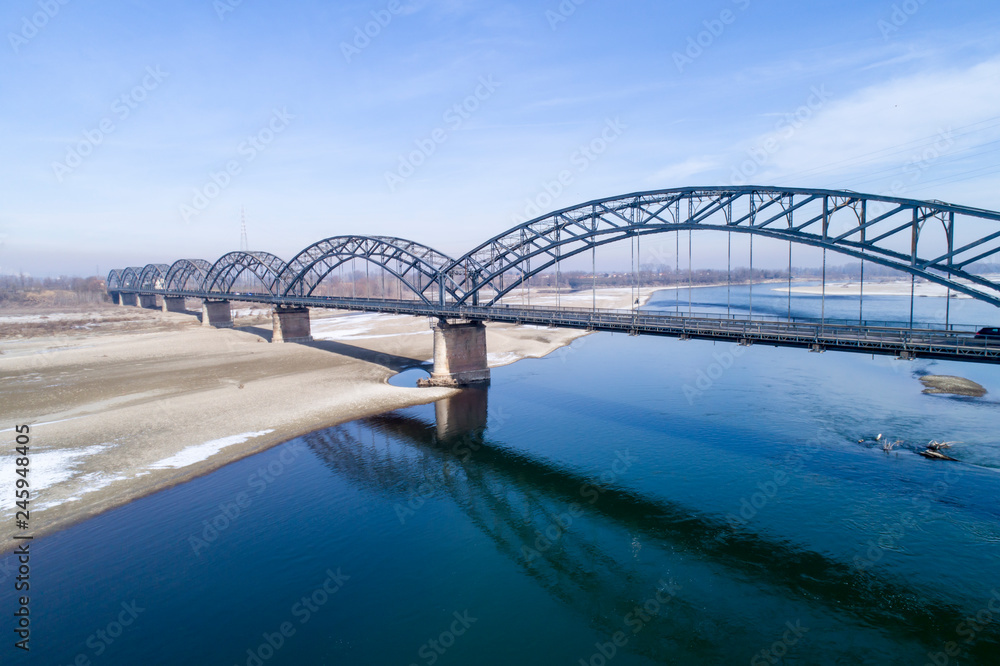 Obraz premium Gerola bridge in winter. Ancient iron bridge, built in 1913, on the river Po in the province of Pavia (Italy). River with little water due to drought.