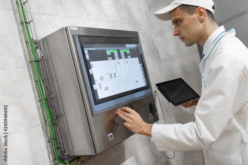 man in a white robe and a cap stands near the digital screen