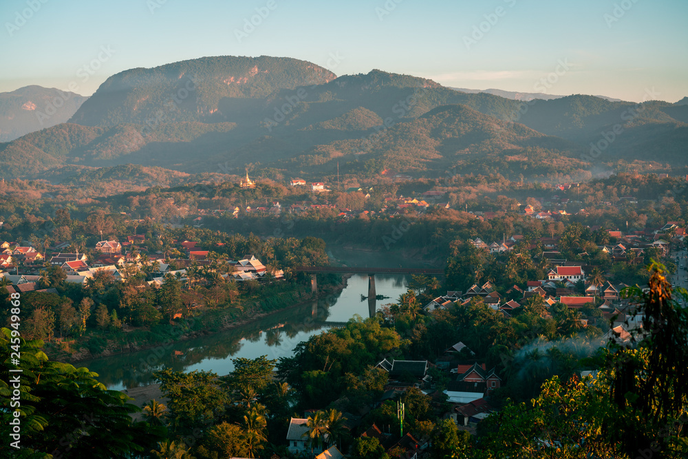 Sunset in Lunag Prabang, Laos. Beautiful clouds over the city. Mekong river between trees and houses. Winter in Laos