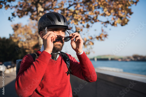 Businessman commuter with bicycle helmet and sunglasses on the way to work in city. © Halfpoint