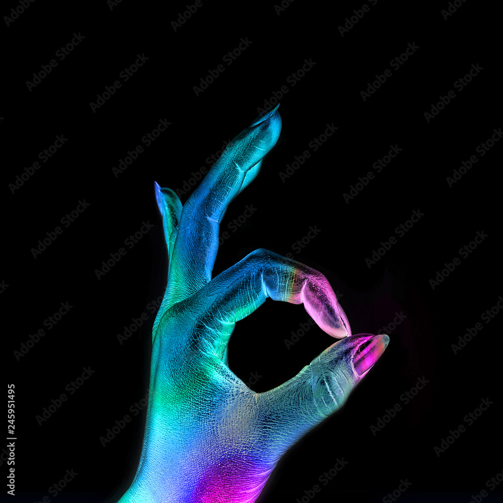 Female hand in the metallic colorful bright neon lights showing OK sign. Minimal concept. Female hand in the metallic colorful bright neon lights showing OK sign. Minimal concept.