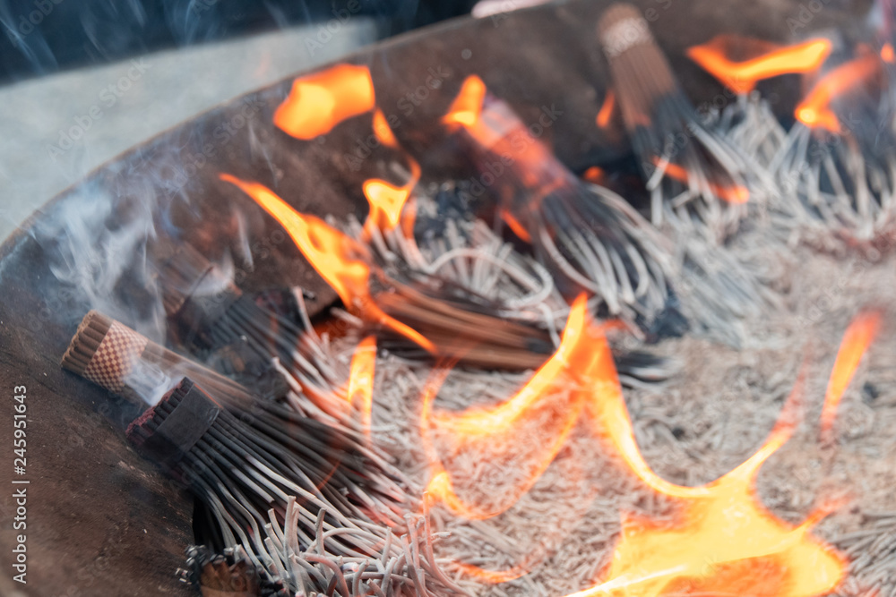 Naklejka premium 線香のお焚き上げ Senko, incense sticks, on fire at Japanese temple for praying.