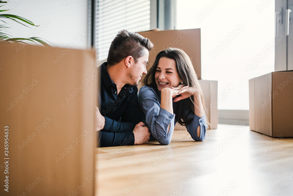 A young couple with a cup and cardboard boxes moving in a new home. A young couple with a cup and cardboard boxes moving in a new home.