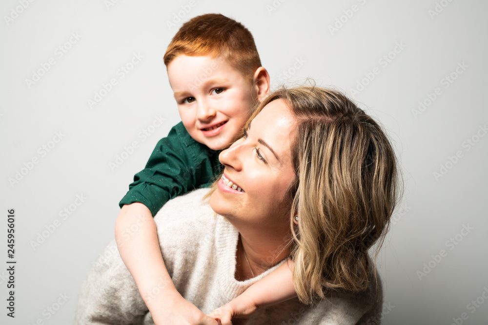A happy young mother with a child on light grey background A happy young mother with a child on light grey background