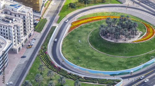 Big roundabout with flowers and grass along main highway, aerial view