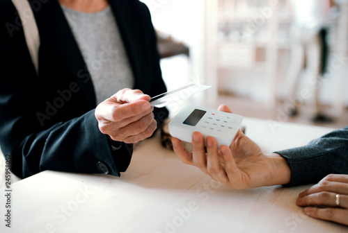 A midsection of customer and shop assistant making contactless payment in a shop. photo