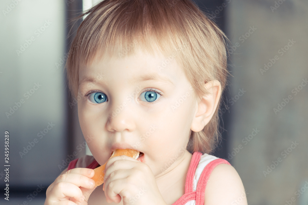Surprised child with big blue eyes eating an orange slice. Surprised child with big blue eyes eating an orange slice.
