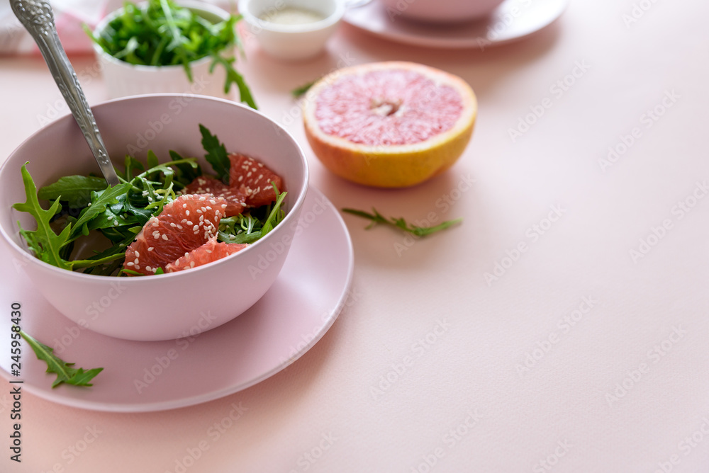 Fresh citrus salad with arugula, grapefruit and sesame seeds on pink background. Selective focus. Raw vegetarian spring detox food. Fresh citrus salad with arugula, grapefruit and sesame seeds on pink background. Selective focus. Raw vegetarian spring detox food.