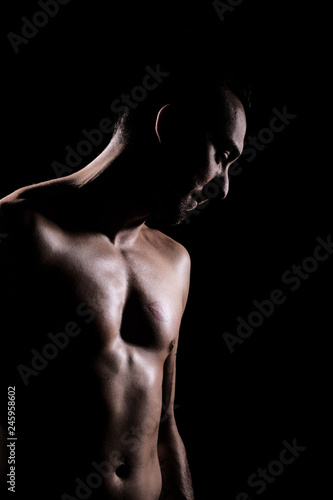 Sexy Mann mit nacktem Oberkörper sinnlich in Licht und Schatten photo