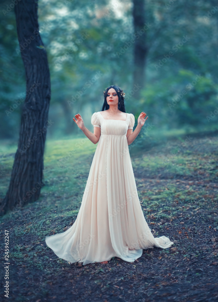 Mysterious lady in a white vintage dress, lost in the woods. Black long hair is decorated with a golden laurel wreath, like that of the Greek Goddess. Creative, artistic colors