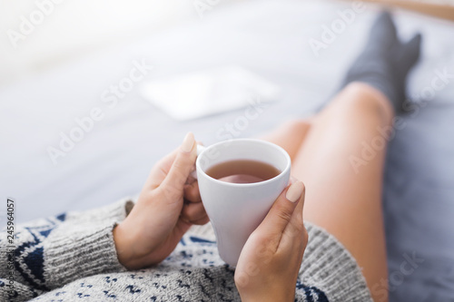 Woman resting in bed with cup of tea