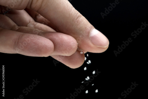 Hands spreading salt on black background