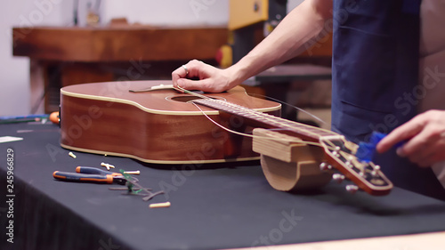 Luthier repairs guitar, changes strings photo