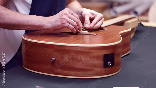 Obraz na plátně Guitarist repairs acoustic guitar strings