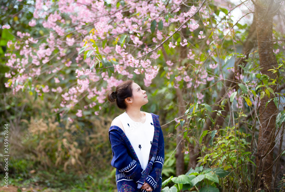 young woman standing outdoor looking at pink flowers young woman standing outdoor looking at pink flowers