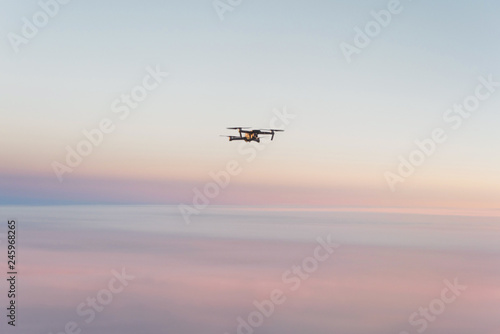Drone quadcopter with digital camera above sunset sky and Earth Surface. Concept of global monitoring and control