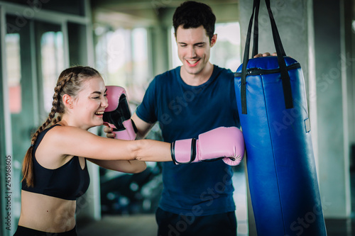 Fit beautiful woman boxer hitting a huge punching bag exercise class in a gym. Boxer woman making direct hit dynamic movement. Healthy, sport, lifestyle, Fitness, workout concept. With copy space. © Shutter B