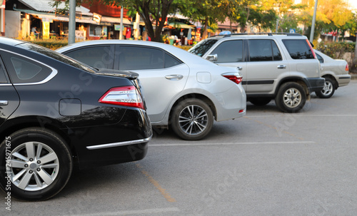 Fototapeta Naklejka Na Ścianę i Meble -  Closeup of back or rear side of black car and other cars parking in parking area with natural background in twilight evening of sunny day. 