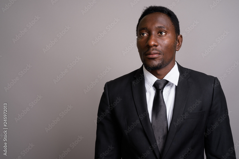 Young handsome African businessman against gray background Young handsome African businessman against gray background