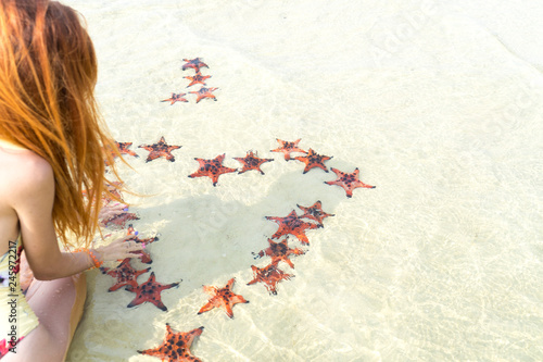 Travel girl with starfishes,making a heart for Valentines Day in honeymoon in Phu Quoc island with clear water and white sand beach