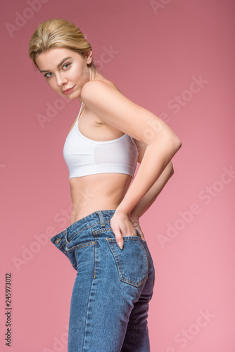 beautiful slim woman posing in jeans and white bra, isolated on pink