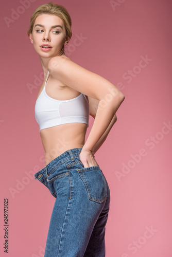 beautiful slim woman posing in jeans and white bra, isolated on pink