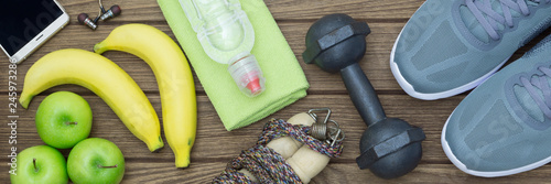 Top view of Healthy lifestyle concept, sport equipments and fresh foods on wood background.  Web Banner.